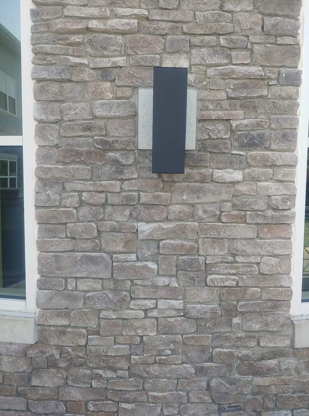 A repaired stacked-stone veneer wall section beside a set of steps.